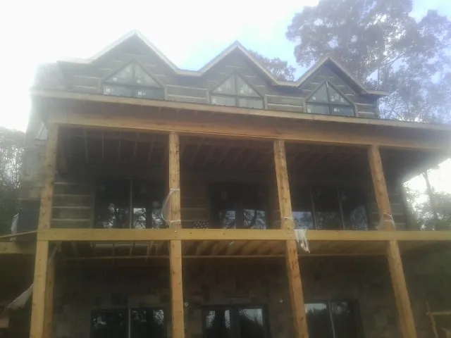 Dormers and porch framing on a large log home under construction — Roof Coating work by our crew in Middleton